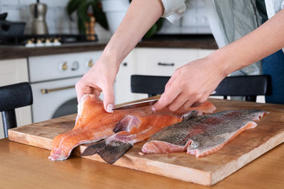 Female hands cutting fillet of red fish. red caviar. removing fish bones. butchering red fish meat.