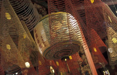 Low angle view of spiral incense sticks with lantern in temple