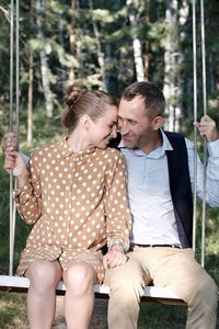 Midsection of couple holding hands sitting outdoors