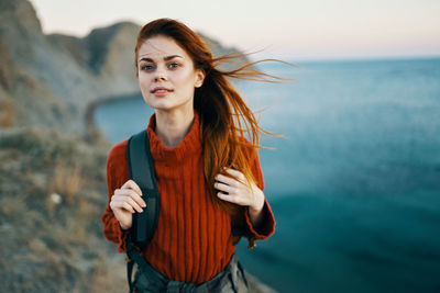 Portrait of beautiful young woman standing against sky