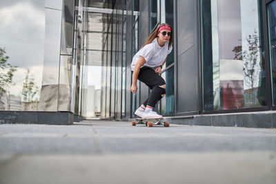 Full length of woman skateboarding on road