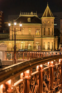Illuminated bridge against old buildings at night