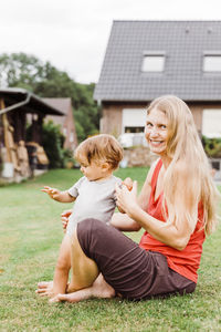 Portrait of woman with baby girl sitting in yard