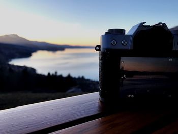 Close-up of camera against sky at sunset