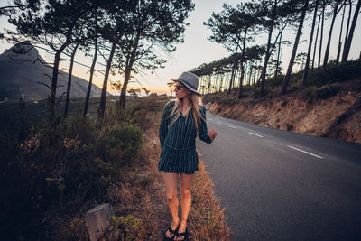 Full length of woman standing on road against trees