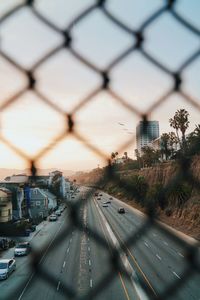 Cars on highway seen through chainlink fence