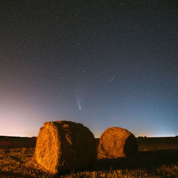 Hay bales on field against sky at night