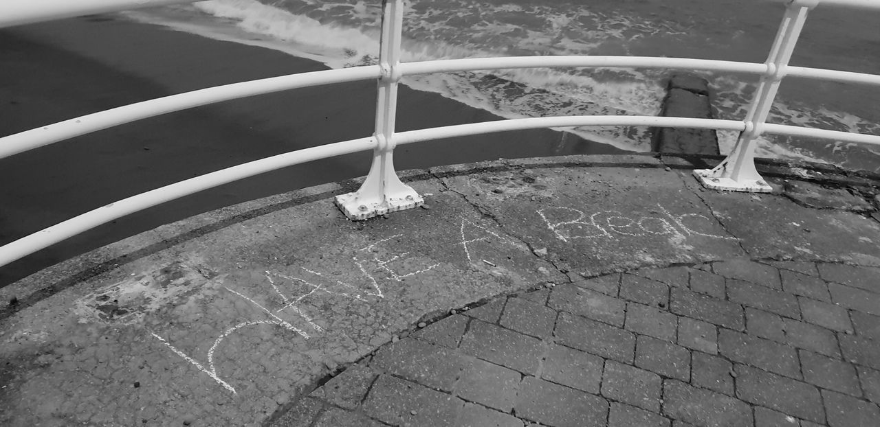 HIGH ANGLE VIEW OF FOOTPATH BY RAILING AGAINST WALL