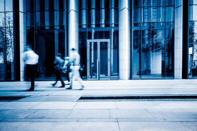 People walking on street by building in city