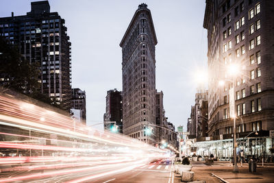 Light trails on urban street against buildings