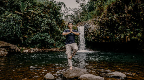  man standing by water fall and plants in forest