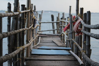 Wooden footbridge over sea against sky