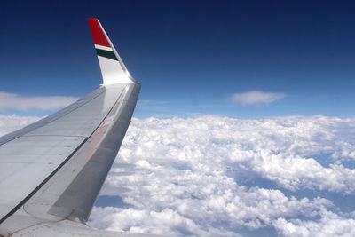 Airplane flying over clouds against blue sky