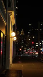 Illuminated street amidst buildings at night