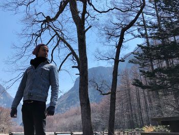 Low angle view of man looking away while standing in forest