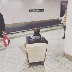 Rear view of woman sitting on wall