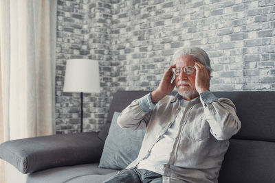 Side view of woman sitting on sofa at home