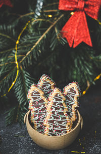 Christmas tree cookies in a craft basket, with selective focus near a blurred christmas tree 