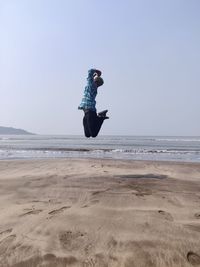 Person jump on beach against clear sky