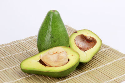 Close-up of green fruit on table against white background