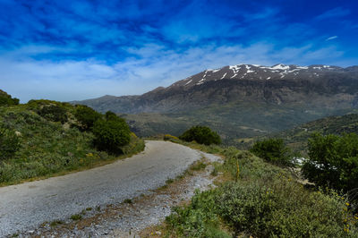 Road by mountains against sky