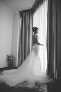 Bride in wedding dress standing by window