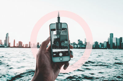 Midsection of man photographing cityscape against sky