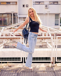 Portrait of young woman standing against building