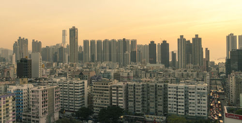 Modern buildings in city against sky during sunset