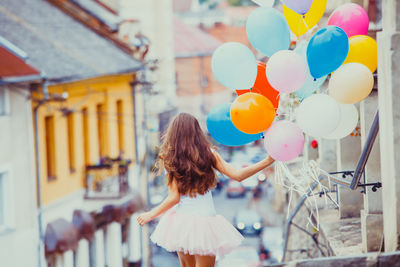 Rear view of woman standing on balloons