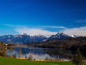 Scenic view of lake by mountains against blue sky