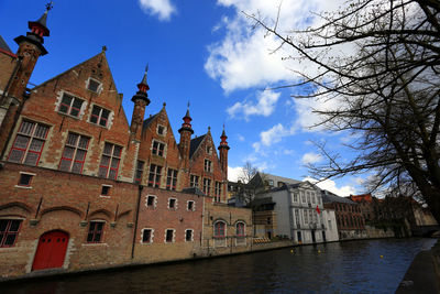 Buildings by river in town against sky