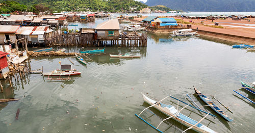 High angle view of fishing boats moored on river amidst buildings