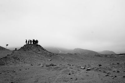 People on arid landscape against sky