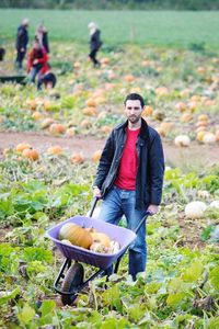 Full length portrait of young man eating basket on field