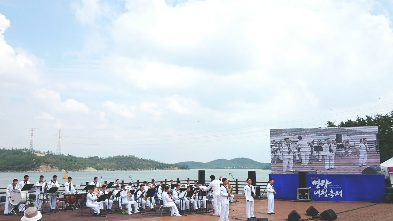 PEOPLE LOOKING AT SEA AGAINST CLOUDY SKY