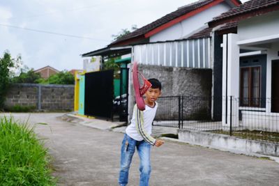 Portrait of smiling young woman standing outside house