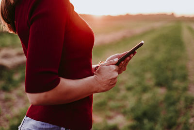 Midsection of person holding mobile phone outdoors