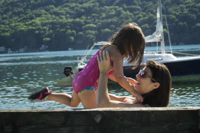 Mother carrying daughter by lake