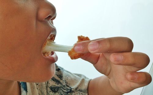 Close-up of boy eating cheese ball at home