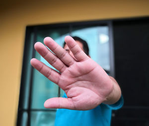 Man showing stop gesture while standing against window