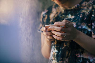 Midsection of young woman using mobile phone against wall