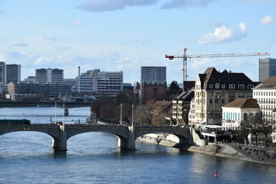 Bridge over river by buildings against sky