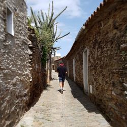 Man walking on road along buildings