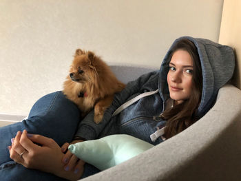 Portrait of woman with dog lying on sofa