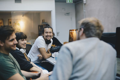 Happy computer programmers talking at desk in office