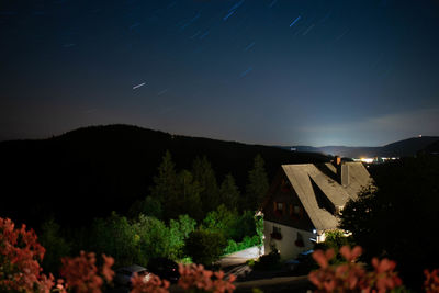 Trees and buildings against sky at night