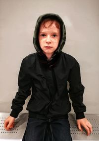 Portrait of young man standing against wall