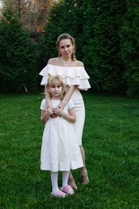 Portrait of mother and daughter in dress standing on field