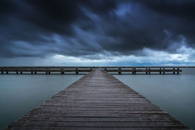 Pier over sea against cloudy sky